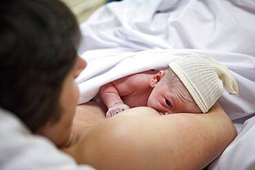 In the delivery room, skin to skin contact and first attempt at breast-feeding.