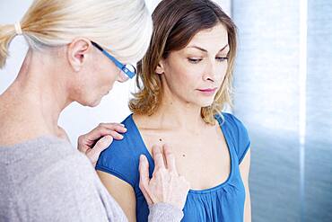 Doctor examining the upper chest of a patient.