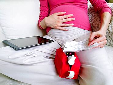 Pregnant woman reading medication instruction sheet.