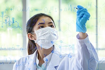 Asian young girl student scientist is writing and researching in laboratory.