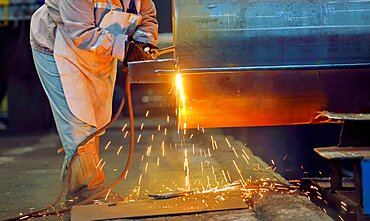 Woman and blowtorch inside of factory.