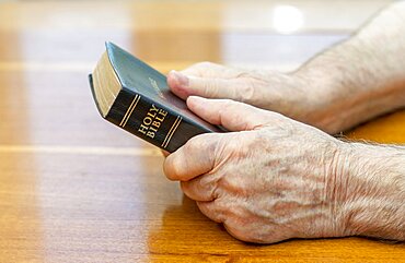 Holding the bible over table.