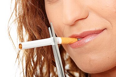 Young woman quiting smoking, isolated on white - focus on hand.