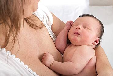 Asleep baby in mother's arms.