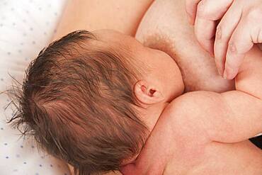 Mother breast feeding 2-week-old baby.