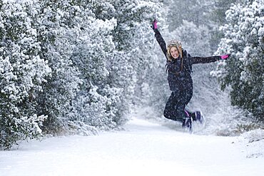 Caucasian young woman enjoying jumping in snow outdoor in winter time. Navarre, Spain, Europe.