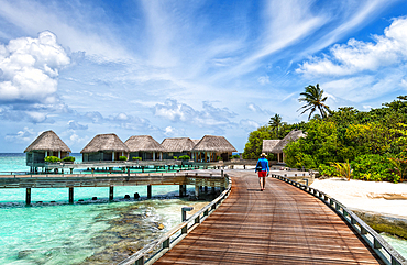 Man walking on a wooden jetty, Baa Atoll, Maldives