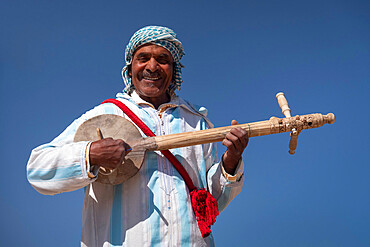 Moroccan man in traditional dress playing a traditional Gimbri instrument, Ouarzazate, Atlas Mountains, Morocco, North Africa, Africa