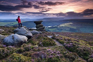 Walker looking out from the distinctive Salt Cellar rock formation on a heather moorland in summer, Derwent Edge, Peak District National Park, Derbyshire, England, United Kingdom, Europe