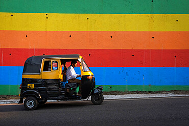 Indian Tuk Tuk passing a brightly painted wall in Panjim City, Panjim (Panaji), Goa, India, Asia