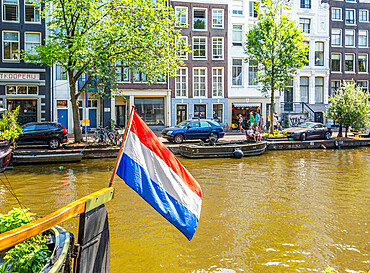 The Dutch flag flying from a houseboat on the Prinsengracht canal, Amsterdam, North Holland, The Netherlands, Europe