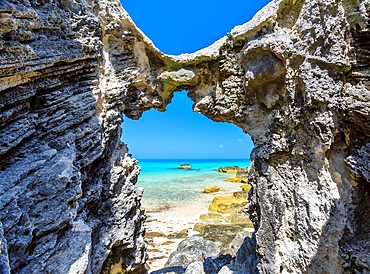 Blue and turquoise Sargasso Sea, glimpsed through an arch in the island's distinctive rocks, Bermuda, Atlantic, North America