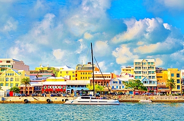 Catamaran passing pastel coloured buildings on Front Street, Hamilton, Bermuda, Atlantic, North America