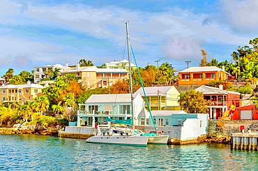 Catamaran in The Great Sound, moored in front of typical pastel coloured properties, Bermuda, Atlantic, North America