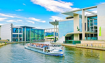 A tour boat on the River Spree passing the Library of the German Parliament (right) near the Reichstag building.