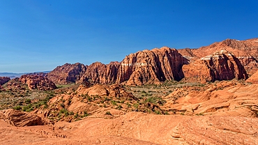 The Red Mountains rising behind the petrified sand dunes at Snow Canyon State Park, Southern Utah, USA. Many famous films were made in the park which forms part of the Red Cliffs Desert Reserve.