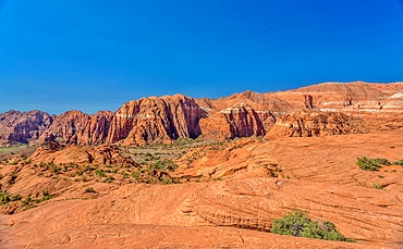 The Red Mountains rising behind the petrified sand dunes at Snow Canyon State Park, Southern Utah, USA. Many famous films were made in the park which forms part of the Red Cliffs Desert Reserve.