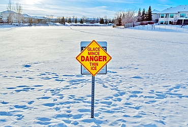 Sign warning of thin ice on a frozen lake in Linden Ridge, Winnipeg, Manitoba, Canada.