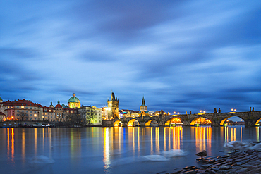 Charles Bridge, OId Town Bridge Tower and dome of St. Francis of Assisi Church by Vltava River at twilight, Prague, Czechia, Europe