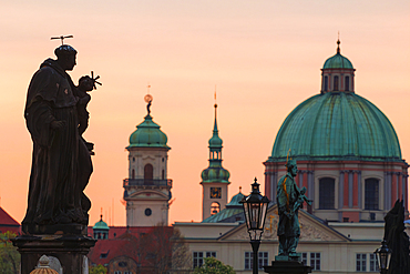 Statue at Charles Bridge with a dome of St. Francis of Assisi in the background at sunrise, UNESCO World Heritage Site, Prague, Czech Republic (Czechia), Europe