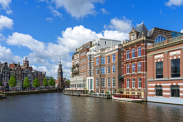 Houses by Amstel River and Munttoren tower in background, Amsterdam, The Netherlands