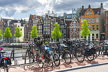 Bicycles with houses by Amstel River in background, Amsterdam, The Netherlands