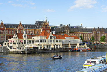 Boat on canal in front of Amsterdam Central Train Station, Amsterdam, The Netherlands