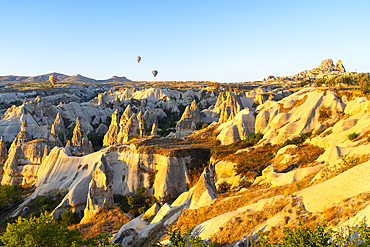 Rock formations with distant views of Uchisar Castle at sunrise, Goreme, Cappadocia, Anatolia, Turkey, Asia Minor, Asia