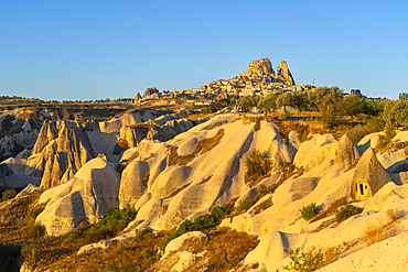 Rock formations with distant views of Uchisar Castle at sunrise, Goreme, Cappadocia, Anatolia, Turkey, Asia Minor, Asia