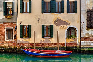 An empty red and blue boat moored in Rio della Misericordia, Venice, Veneto, Italy