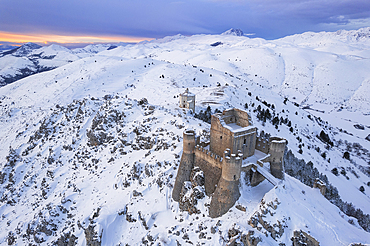 Aerial winter view of Rocca Calascio castle and the Santa Maria della Pietà church in the snowy landscape at dusk, Campo Imperatore, L'Aquila province, Abruzzo region, Italy, Europe