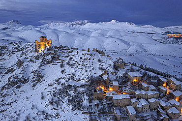 Winter view of the snow covered illuminated medieval village of Rocca Calascio with the castle at dusk, Rocca Calascio, Gran Sasso e Monti della Laga National Park, Campo Imperatore, L'Aquila province, Abruzzo region, Italy, Europe