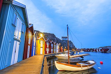 Colorful fishing huts with wooden boat moored at the jetty at dusk, Smogen, Bohuslan, Vastra Gotaland, West Sweden, Sweden, Scandinavia, Europe