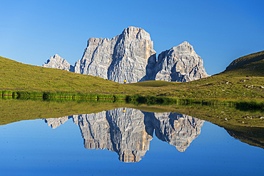 Hiker and Mount Pelmo reflected in the water of Baste Lake on a sunny day, Belluno Dolomites, Belluno province, Veneto, Italy, Europe