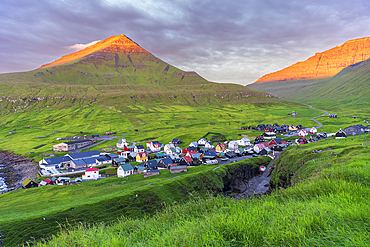 Colorful houses of the village of Gjogv with the mounatins lit by the early sun, sunrise view, Eysturoy island, Faroe islands, Denmark, Europe