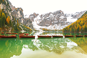 Wooden boats floating on calm waters of Braies lake, autumn view, Braies, South Tyrol, Bozen province, Italy, Europe