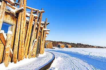 Architectural structure of Arctic Bath hotel made of logs on frozen Lule River with cutting-edge chalets in the background, Harads, Norrbotten, Swedish Lapland, Sweden, Scandinavia, Europe