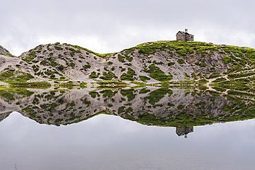 The small church and the reflection of the alpine landscape in the calm water, Olbe lakes, Sappada, Carniche Alps, Udine province, Friuli-Venezia Giulia, Italy, Europe