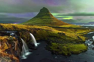 Kirkjufell mountain and Kirkjufellfoss waterfall with faded Northern Lights (Aurora Borealis) behind clouds, Snaefellsnes Peninsula, Western Iceland, Iceland, Polar Regions