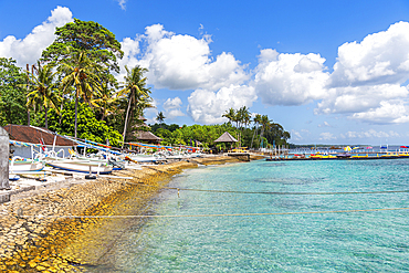 View of a tropical beach with palms and trees along the coast of the island of Nusa Penida, with traditional Indonesian wooden boats (jukung) (kano) (cadik), on the beach, Nusa Penida island, Klungkung regency, Bali, Indonesia, Southeast Asia, Asia