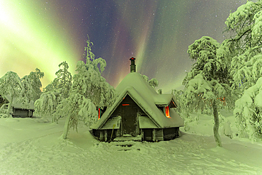 Northern Lights (Aurora Borealis) in the starry sky above a mountain hut in the snow-covered wood of Finnish Lapland, Pallas-Yllastunturi National Park, Muonio, Finnish Lapland, Finland, Scandinavia, Europe