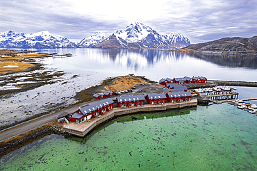 Aerial view of traditional red rorbu surrounded by majestic mountains covered with snow, Vestvagoy, Lofoten Islands, Norway, Scandinavia, Europe