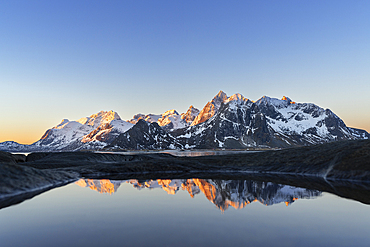 Warm morning lights on snowy mountains reflected in a pool by the fjord, Vareid, Flakstad municipality, Lofoten Islands, Norway, Scandinavia, Europe