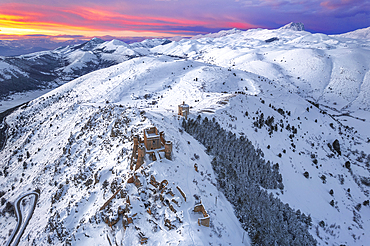 Aerial winter view of the snow covered Rocca Calascio castle and church of Santa Maria della Pieta,�with pink clouds at sunset, Rocca Calascio, Gran Sasso e Monti della Laga National Park, Campo Imperatore, L'Aquila province, Abruzzo, Italy, Europe