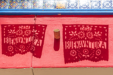 Loreto, Baja California Sur, Mexico. Shadows of banners saying 'good luck' in Spanish, in a market in Loreto.