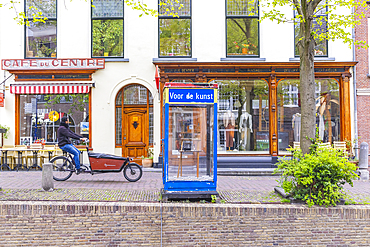 Europe, Netherlands, South Holland, Delft. April 25, 2022. Small shops and man on a cargo bicycle in the city of Delft.