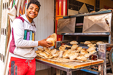 Manshiyat Naser, Garbage City, Cairo, Egypt. February 14, 2022. Young man selling fresh pita bread, known as aish, in Manshiyat Naser, Garbage City, Cairo.