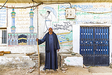 Thebes, Luxor, Egypt. February 26, 2022. Man standing in front of contemporary murals on in Luxor.