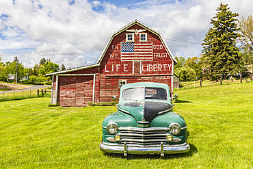 Latah, Washington, USA. May 24, 2021. Vintage Plymouth Super De Luxe automobile and a weathered red a barn. Editorial Use Only