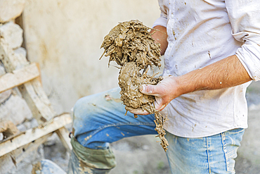 Mavzoley Rudaki, Sughd Province, Tajikistan. Worker applying mud plaster to a traditional stone house.